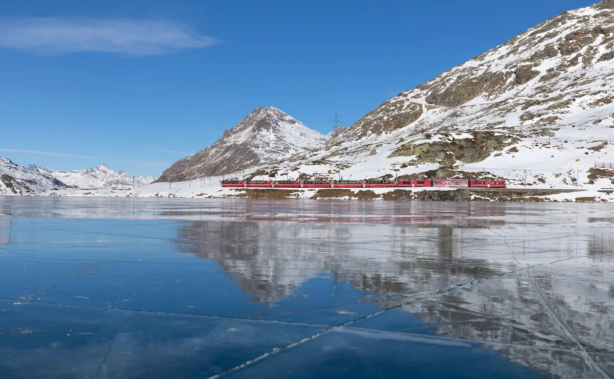 Ein Bernina Express spiegelt sich im Lago Bianco