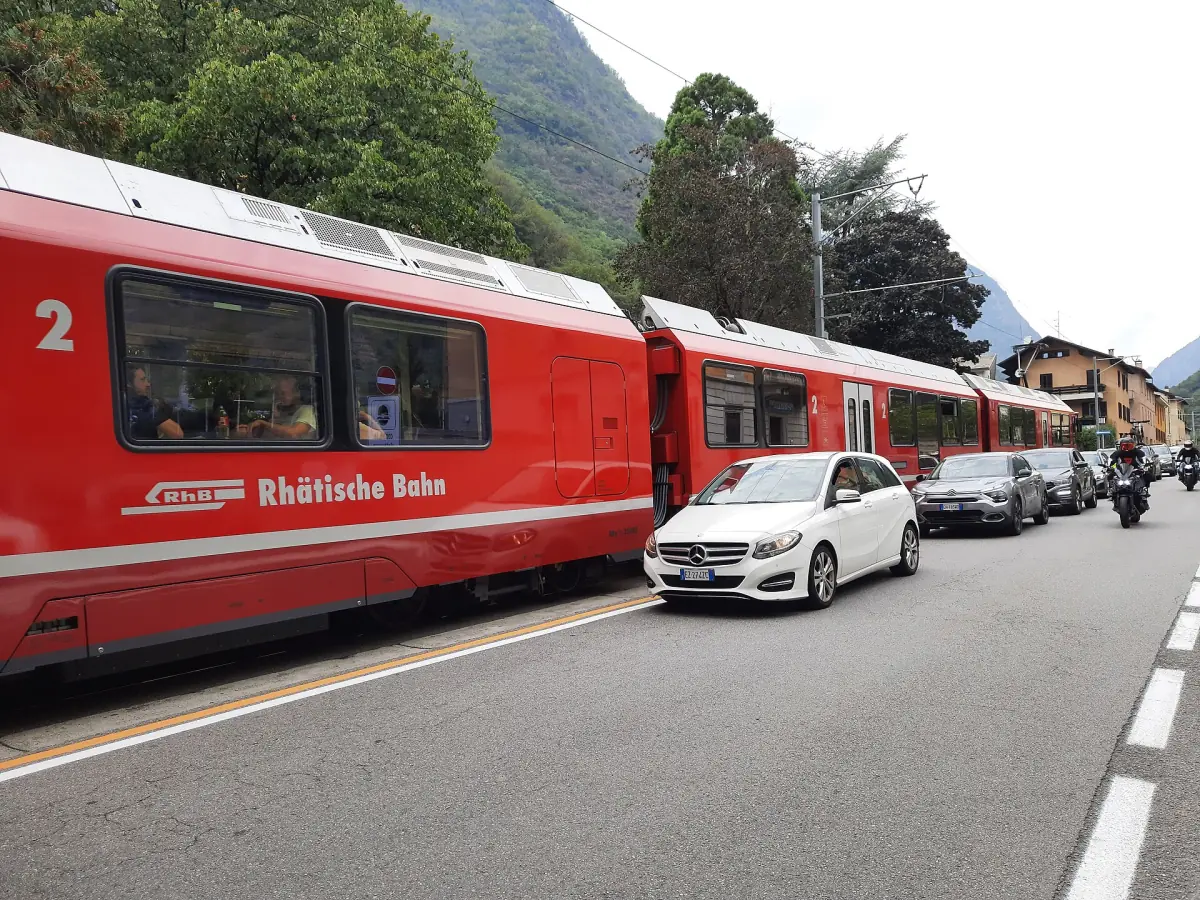 Ein roter Zug der Berninabahn auf der Straße in Tirano