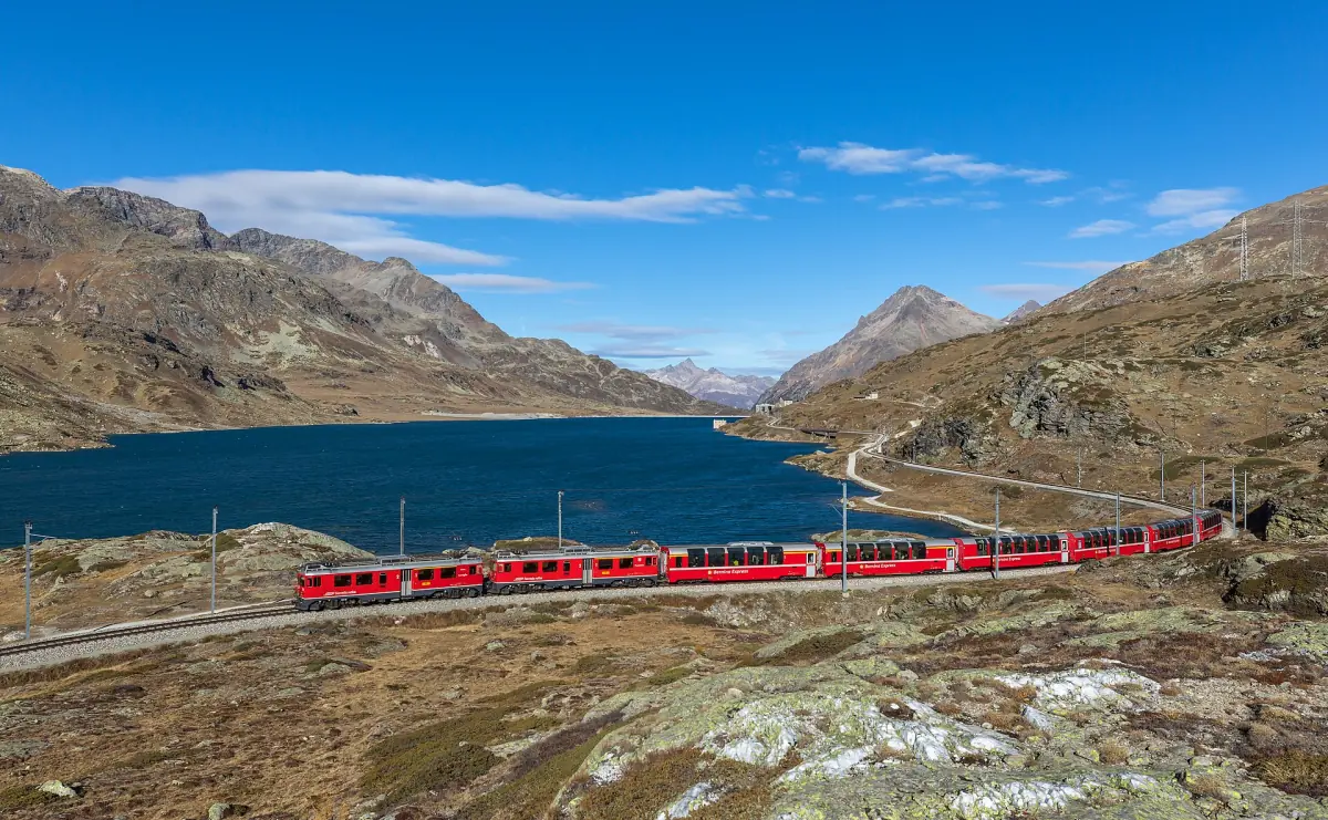 Ein roter Zug der Berninabahn am Lago Bianco im Herbst
