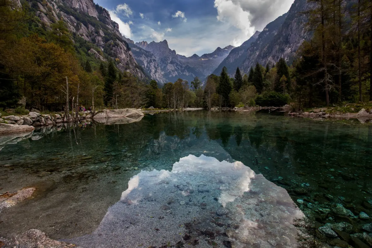 Berge spiegeln sich im stillen Wasser im Val di Mello